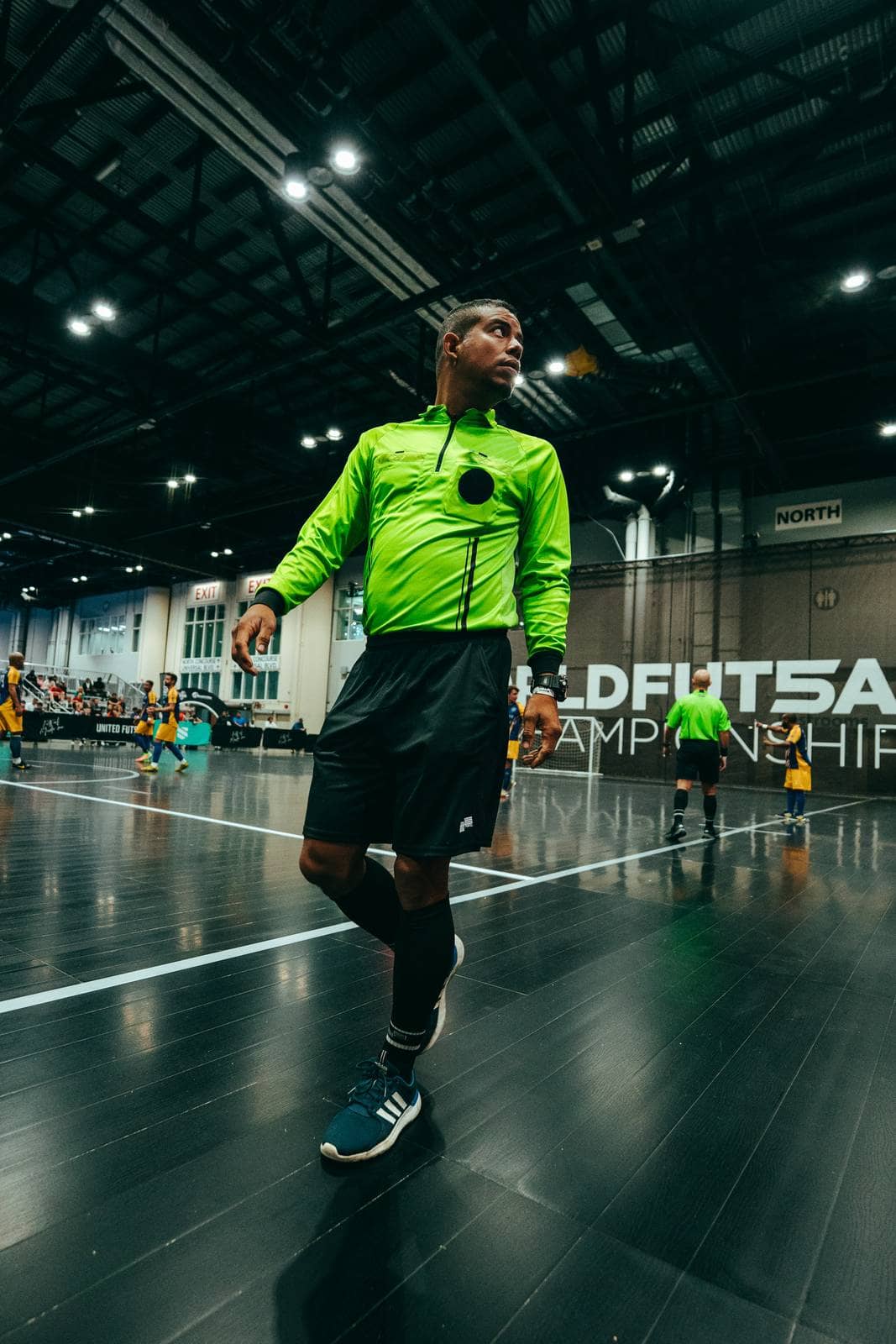 A referee moves across the court with two officials behind him