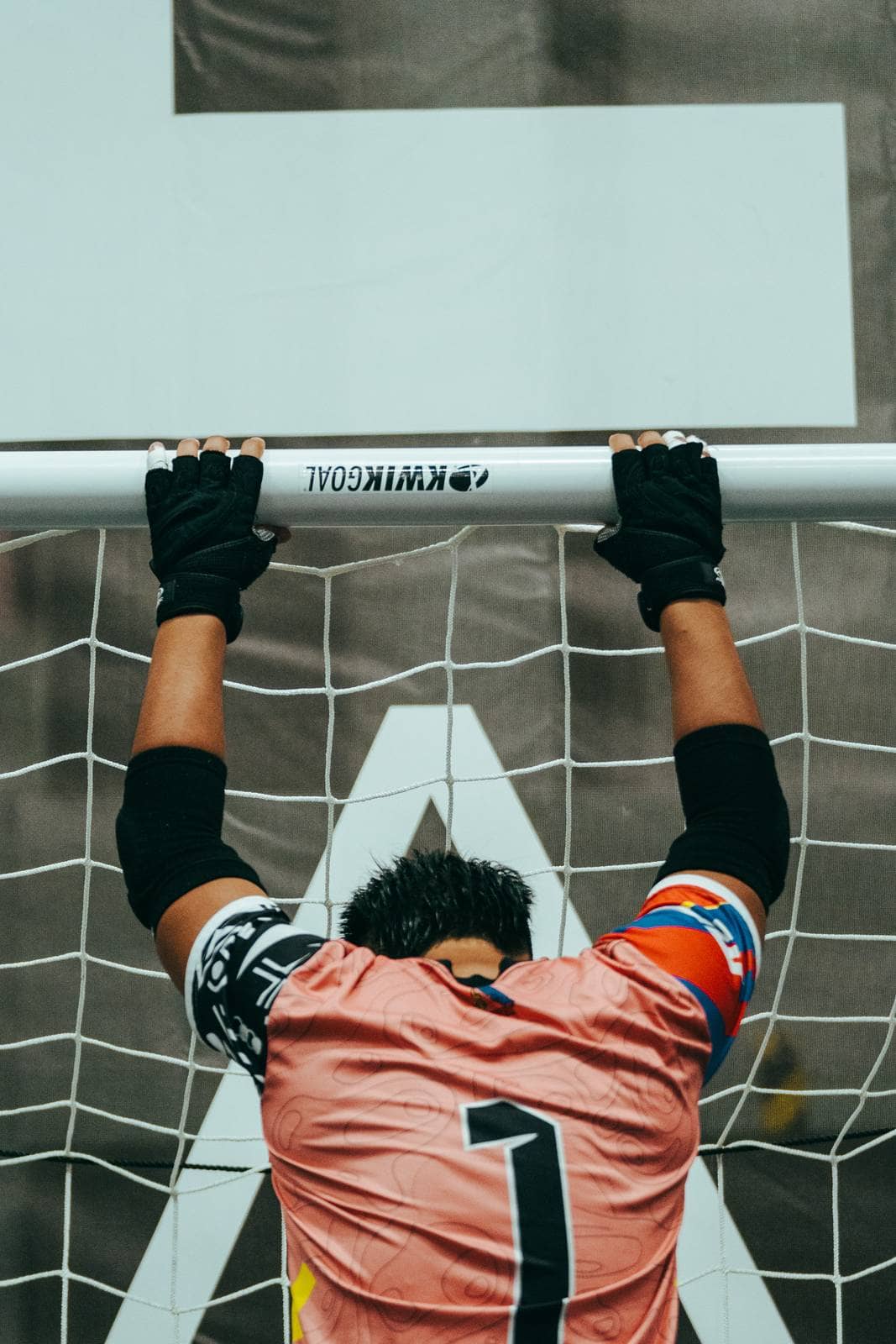 A goalkeeper grips the crossbar with his head bowed