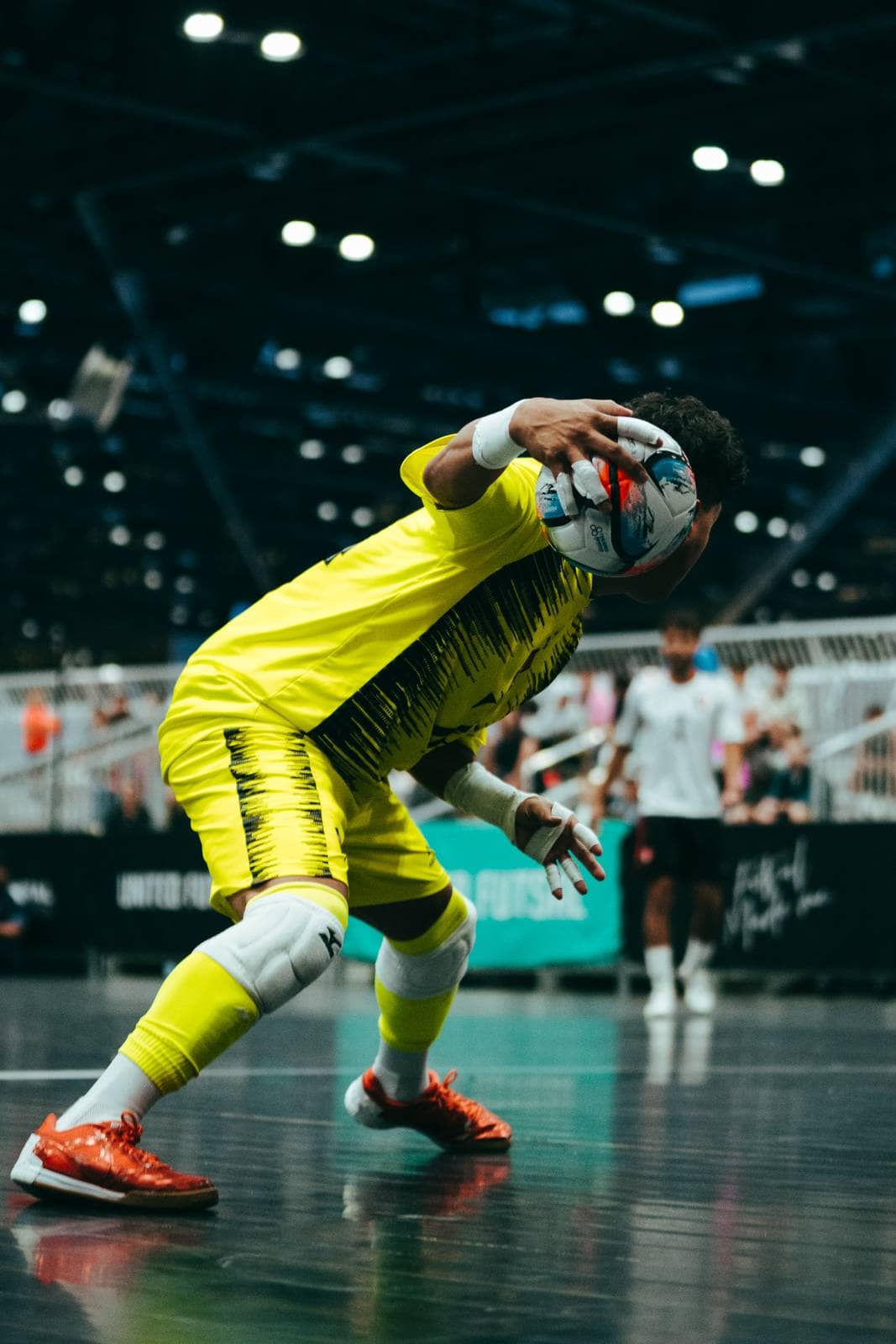 A goalkeeper bends low to hold on to the ball