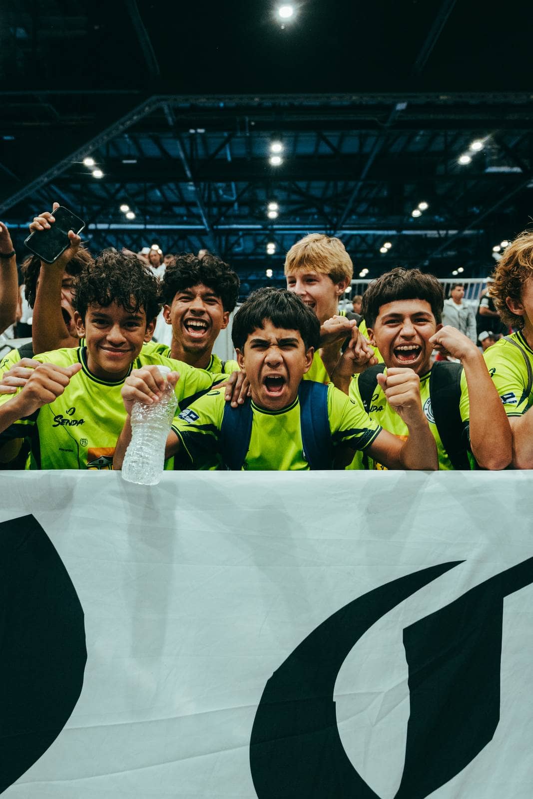Young players cheer from behind a banner